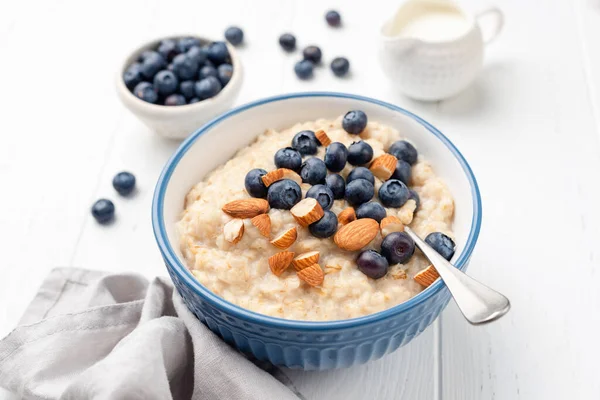 Healthy breakfast oatmeal porridge in bowl with blueberries and almonds