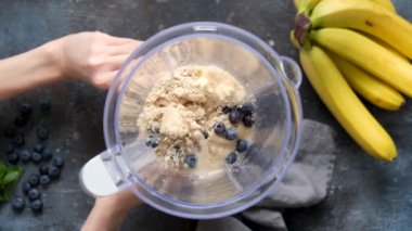 Protein içeceği hazırlarken üst görünüm yavaş çekim. Protein yabanmersinli muzlu smoothie karışımı ya da yavaş çekimde karıştırılıyor. Sağlıklı vejetaryen yemekleri