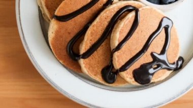 Çikolata soslu krepler ve ahşap masada böğürtlenler, üst manzara. Lezzetli tatlı kahvaltı yemekleri.