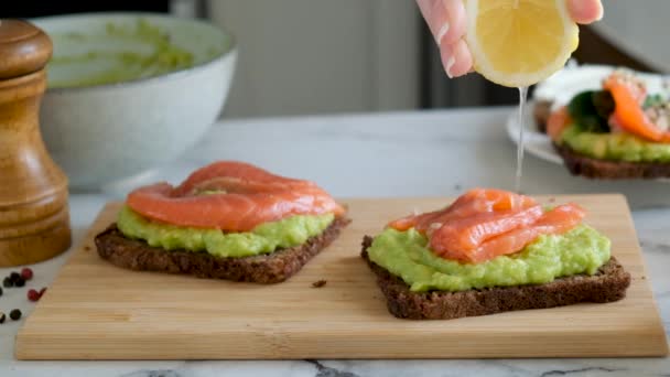 Slow motion of chef squeezing lemon on rye bread toast with avocado and salmon fish. Healthy appetizer, breakfast or snack food — Stock Footage Slow Motion Chef Squeezing Lemon Rye Bread Toast Avocado Salmon Stock Footage