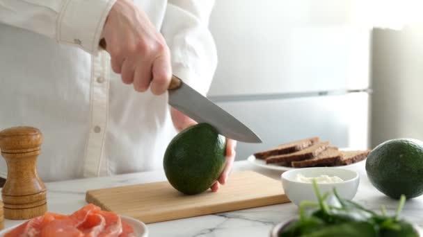 A séf félbevágja az avokádót a konyhában. Egészséges ételek főzése