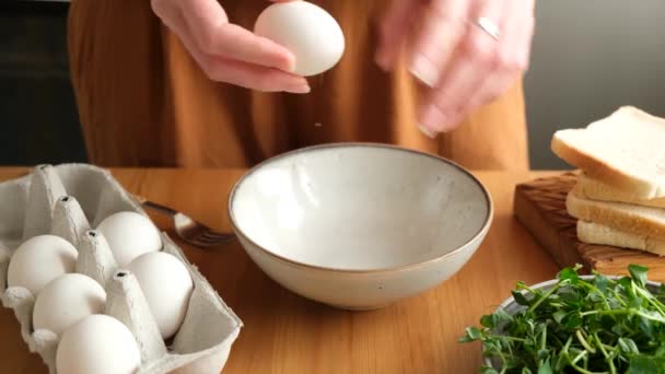 卵をボウルに入れる 女性は朝食のオムレツやスクランブルエッグを準備します 家庭用木製キッチンテーブル 調理朝食 — ストック動画