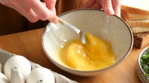 ゆっくりとゆで卵のためのフォークで卵を混合泡立て器の動き 家庭生活 オムレットやスクランブルエッグを作る女性 キッチンでの朝食の調理 — ストック動画