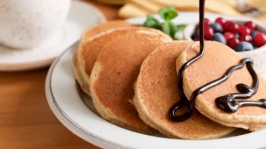 Kreplerin üzerine çikolata sosu dökerken yavaş çekimde. Lezzetli tatlı kahvaltı yemekleri.