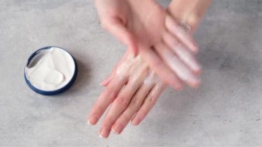 Kadın elleri gri beton arka planda el kremi sürüyor. Spa, cilt bakımı terapisi