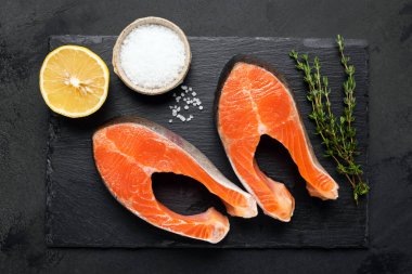 Siyah tahtada somon bifteği, tuz ve otlar.