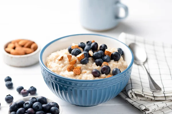 Bowl of oatmeal porridge with blueberries and almond nuts