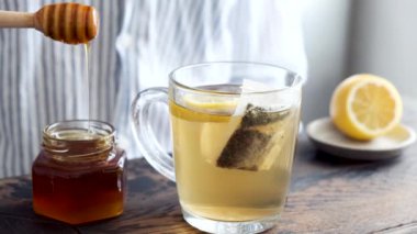Limon çayına bal ekliyorum. Zencefilli yeşil çaya limonlu doğal bal eklemek için ahşap balı kullanan kişi.