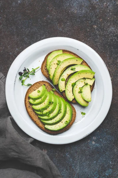 Житній тост зі скибочками авокадо та мікрозеленою зеленню — стокове фото