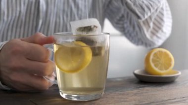 Limonlu yeşil çay, çay poşeti çayı. Erkek insan yeşil çay yapmak için çay poşetini sıcak suya daldırıyor.
