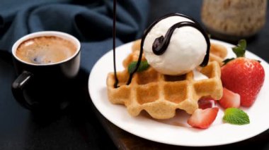 Vanilyalı dondurma ve Belçika waffle 'larına çikolata sosu döküyorum. Vanilyalı dondurma, çilek, çikolata şurubu ve bir fincan espresso kahveli lezzetli Belçika waffleları.