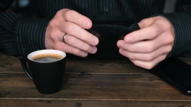 Rüşvet. Erkek eller siyah deri cüzdandan nakit dolar alıp ahşap masaya koyar. Yatırım, rüşvet, ödeme konsepti