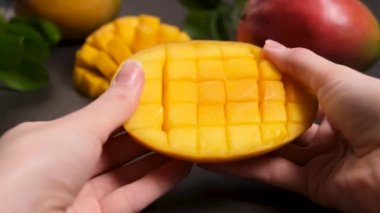 Taze sulu tropikal mango meyvesi ellerinde. Kadın, küp küp kesilmiş mango açar.