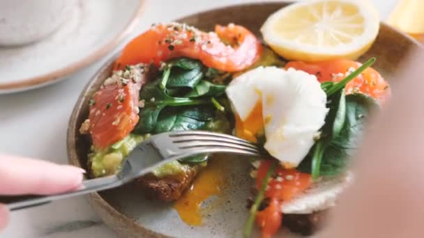 Eating Tasty Sandwich With Salmon Poached Egg Avocado. Lunch Or Breakfast In Cafe. Gourmet Food — Stock Footage Eating Tasty Sandwich Salmon Poached Egg Avocado Lunch Breakfast Cafe Stock Video