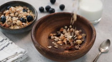 Kuru üzümlü ve fındıklı yulaf ezmesi kaseye düşüyor. Sağlıklı kahvaltı gevrekleri. Temiz yemek, diyet konsepti.