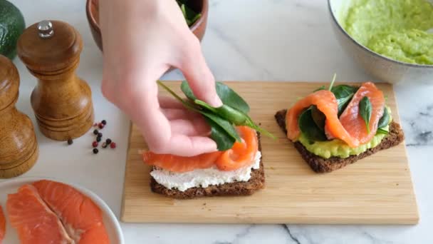 健康的なスナックや前菜トーストサーモン アボカドマッシュとほうれん草 食料の準備 — ストック動画