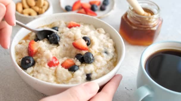 朝食はベリーとオートミール 新鮮なベリーや蜂蜜とお粥のオート麦を混合し オート麦のスプーンを取る人 — ストック動画