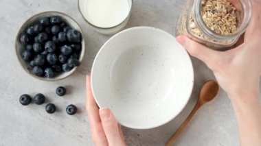 Sağlıklı kahvaltı gevreklerini kaseye koyan kadın. Fındıklı ve kuru meyveli yulaf ezmesi. Temiz yemek, diyet, fitness menüsü konsepti