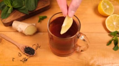 Zencefil çayına limon ekliyorum. Tahta bir masada sağlıklı bir grip önleyici sıcak içecek. Alternatif ilaç bitki çayı.