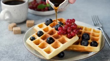 Böğürtlenli Belçika wafflelarının üzerine şurup dökülüyor. Akçaağaç şuruplu tatlı şekerli waffle.