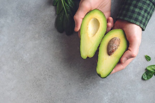 Руки, держащие половинки авокадо — стоковое фото