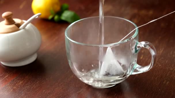 Brasser le thé noir avec un sachet de thé dans une tasse en verre sur une table en bois 