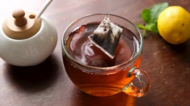 Tahta masada cam fincanda çay poşeti kullanarak siyah çay.