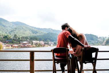 Bir çift, Tayland 'daki Rak Thai köyünde gölün önünde sevgi gösteriyorlar..