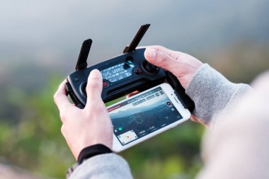 Genç adam uzaktan dronu kontrol ediyor. Kendi başına göremediği manzarayı görmek için..
