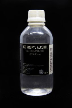 Siyah arka planda tıbbi ve endüstriyel kullanım için bir şişe ISOPROPYL ALCOHOL (% 99 saf). Renksiz, yanıcı kimyasal bileşik, kimyasal formül CH3CHOHCH3, alkol antiseptik
