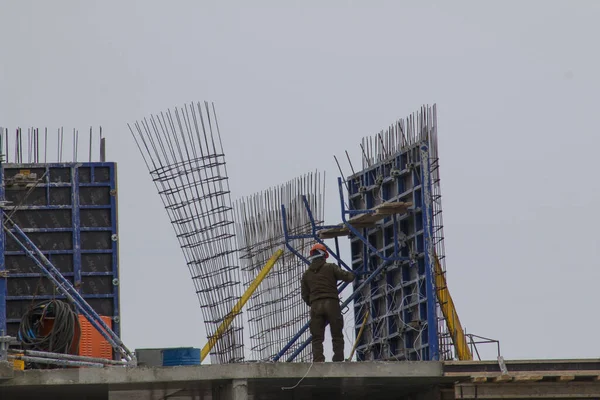 A worker in a helmet works at the height of a house under construction.