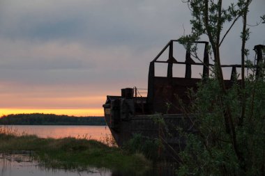 Sahile yakın büyük eski bir mavna batan arka planda çalılarla kaplanmış. Navigasyon bekleniyor