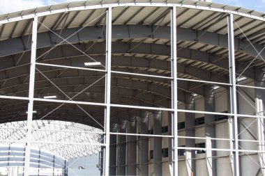 Büyük bir spor merkezinin çatısı yapım aşamasında. Metal elementlerden yapılmış büyük bir yapı. Kemerli yapı