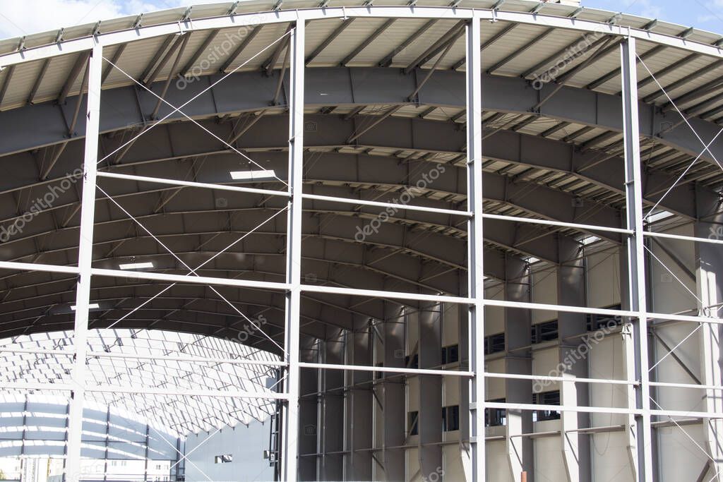 elements of the huge roof of a sports center under construction. Large construction made of metal elements. Arched construction