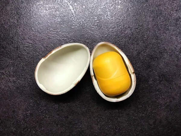 Easter open chocolate kinder egg with a yellow core on a black table
