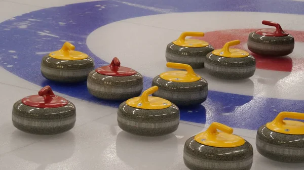 Curling granite stones on ice curling sheet with red and blue circle and visible pebbles. Winter team olympic sport.