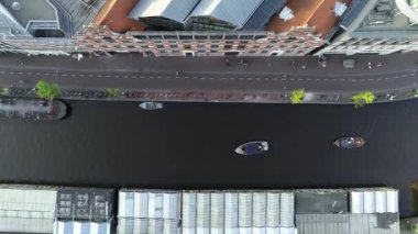 Amsterdam, Hollanda 4K 'da. Kanal ve eski merkez bölge üzerindeki hava manzarası. Ünlü Amsterdam kanalları, parti tekneleri ve tipik Hollandalı evleri. Şehrin manzarası ve sokaklar sıcacık renklerle dolu.