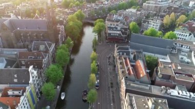 Amsterdam, Hollanda 4K 'da. Kanal ve eski merkez bölge üzerindeki hava manzarası. Ünlü Amsterdam kanalları, parti tekneleri ve tipik Hollandalı evleri. Şehrin güzel, sıcacık renkleri.