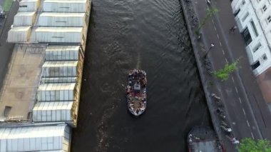 Gün batımında Amsterdam Kanalı yukarıdan görülüyor. Şehrin ortasında yelken açan parti teknesinin havadan görüntüsü. İnsanlar eğleniyor. Hollanda, Hollanda 'da faaliyetler.