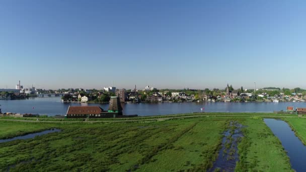 有名な場所 ザーンセスカンスの歴史的な風車 ザーンディークとアムステルダムオランダの近くのザーンダムの空中ドローンビュー 春か夏の晴れた日 アヒルが飛んで人々が自転車に乗っている — ストック動画