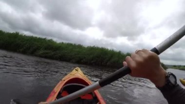 Birinci şahıs POV Bakış açısı. Kano ya da kano manzarası. Su üzerindeki kanonun içinden görüntüler. Nehirde kürek çeken bir adam, ebediyen yeşil. Yaz ya da bahar, bulutlu hava yağmur yağabilir.