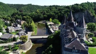 Belçika 'nın Durbuy kentindeki eski kasaba ve kalenin havadan görünüşü, yaz mevsiminde nehirdeki dağlar, nehirler ve kayakçılarla çevrili. Şehrin Panoraması
