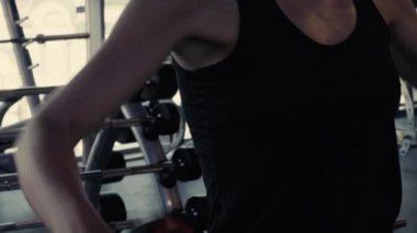 Formda ve genç bir kadın spor salonunda ya da spor salonunda dambıllarla çalışıyor.