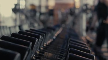 Spor salonunda ya da spor salonunda. Üst üste dambıl seçimi. Kadınlar egzersiz ya da kas geliştirme için dambılları yerine koyuyorlar. Bir sürü ekipmanı olan özel bir spor salonu.. 