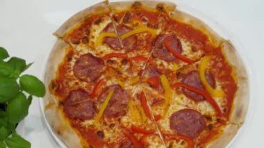 İnsanlar aynı anda bir dilim pizza yiyorlar. Pizzacıda oturan dört arkadaş grubu yeşil fesleğenli beyaz bir masada aynı anda bir dilim pizza yer.. 