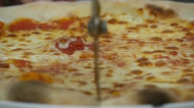 Pişirilmiş pizza, yuvarlak pizza bıçağıyla kesilir. İtalyan pizzacılarının içinde, mükemmel pizza hazırlama süreci
