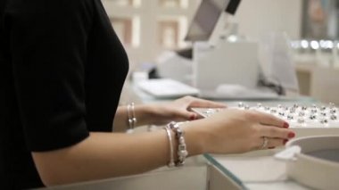 Lüks bir kuyumcuda, satıcı kadın güzel yüzükler, küpeler ve bileziklerle dolu bir palet gösterir. Kavram: Uluslararası Kadınlar Günü, Birbirine aşık çiftler, Sevgililer Günü