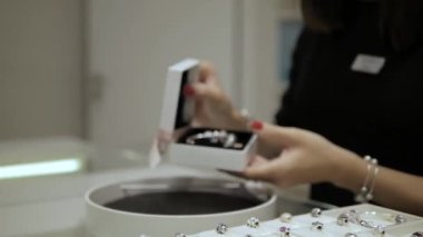 Lüks bir kuyumcuda, satıcı kadın müşteriye güzel bir bilezik gösterir. Diğer mücevherler görünür, gümüş, altın, kristal ve elmaslar. Kavram: Uluslararası Kadınlar Günü, Sevgililer Günü