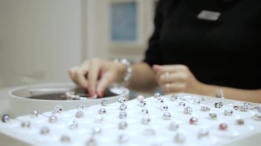 In a jewelry shop: Saleswomen or owner of a jewelry store is showing a beautiful jewelry (charms with stones) to a client. Concept: international Women's day, Valentines day, luxury, idea for a gift