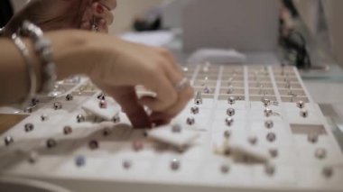 In a jewelry shop: Saleswomen or owner of a jewelry store is showing a beautiful jewelry (charms with stones) to a client. Concept: international Women's day, Valentines day, luxury, idea for a gift